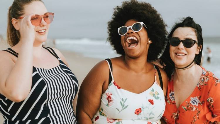 Drei Frauen unterschiedlicher Hautfarbe und Figut lachen